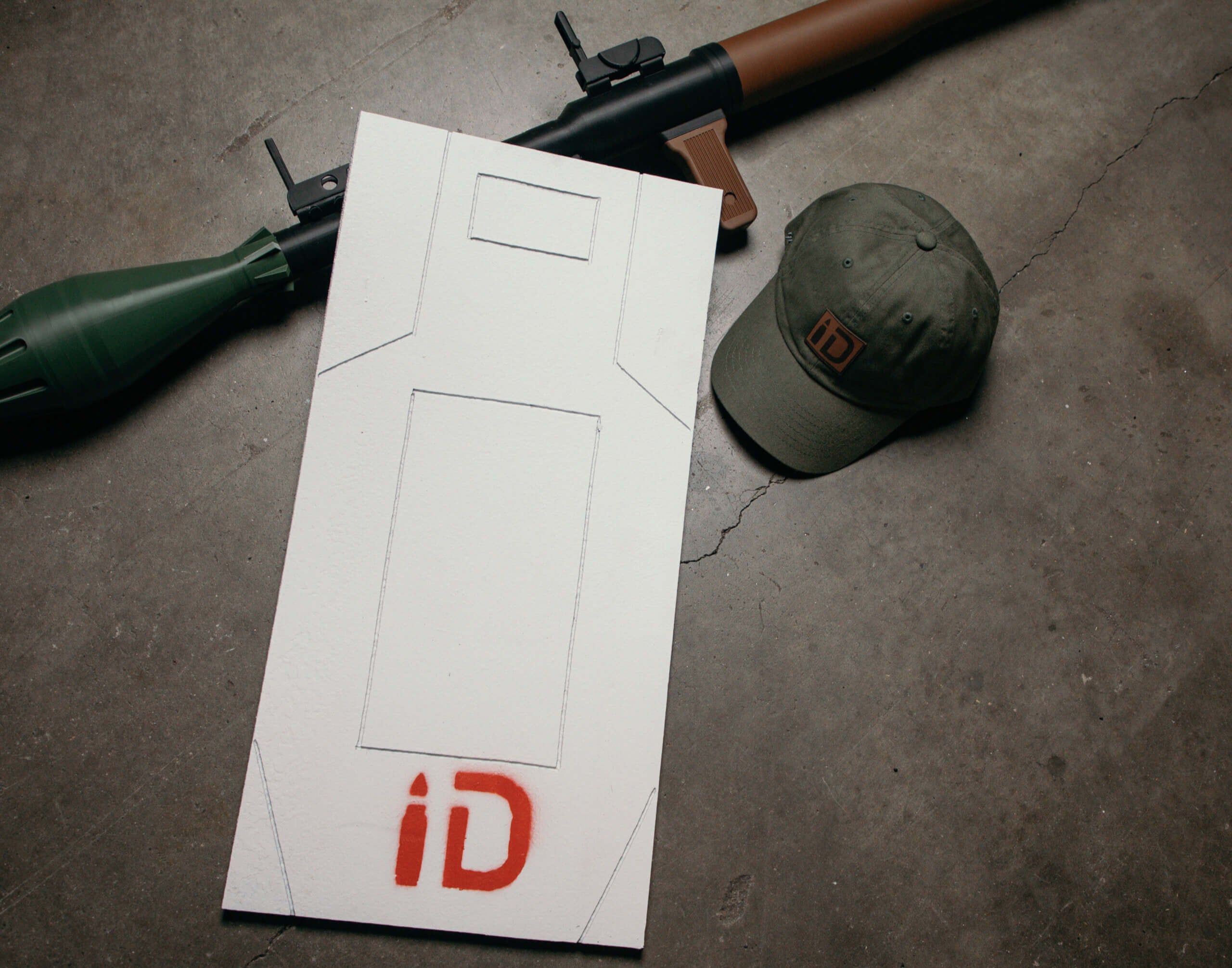 Weapon, cap, and paper with 'iD' logo on a concrete floor - EDC Gear and gifts
