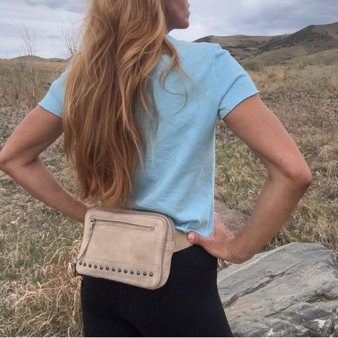 Person wearing a light blue shirt and beige waist bag in a natural setting. Concealed Carry Kailey Leather Purse Pack - Lady Conceal - Concealed Carry Purse - most popular crossbody bag - crossbody handgun bag - crossbody bags for everyday use - Lady Conceal - Unique Hide Purse - Locking YKK Purse - Fanny Pack for Gun and Pistol - Easy CCW - Fast Draw Bag - Secure Gun Bag